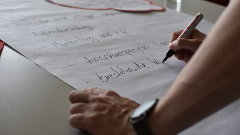 Teilnehmer schreibt auf Plakat