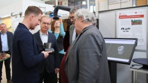 Philipp Henckell zeigt Reinhard Bütikofer ein additiv gefertigtes Bauteil (© Mittelstand 4.0-Kompetenzzentrum Ilmenau)
