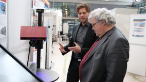 Mathias Eiber stellt Reinhard Bütikofer den Demonstrator zur vernetzten Wertschöpfung vor (© Mittelstand 4.0-Kompetenzzentrum Ilmenau)