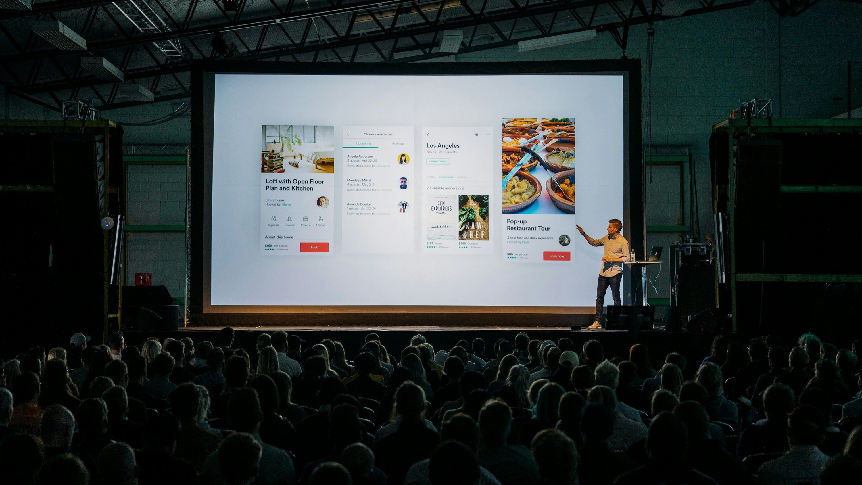 Ein Mann hält einen Vortrag vor vielen Menschen in einem dunklen Raum