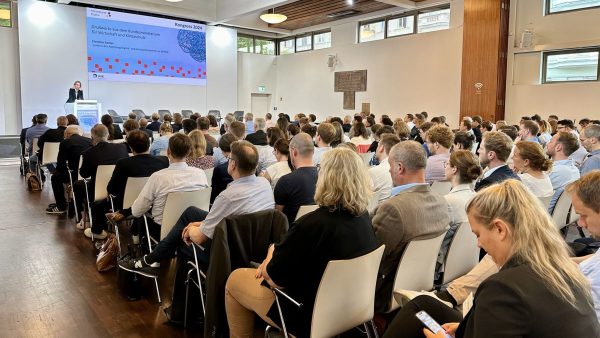 Ein Sall voller Menschen auf Stühlen. Vorn eine Leinwand auf die eine Folie projeziert wird. Christina Decker, Abteilungsleiterin Digital- und Innovationspolitik im BMWK, spricht.