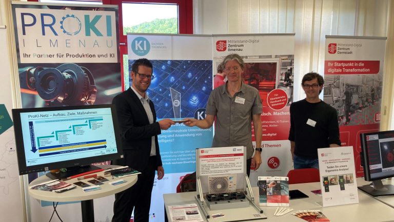 Dr. Sebastian Gerth und Wolfram Kattanek halten den Staffelstab vom KI-Hub hoch.