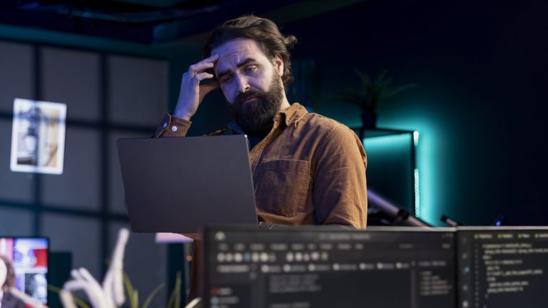 Mensch mit Laptop schaut nachdenklich und hat die Hand am Kopf