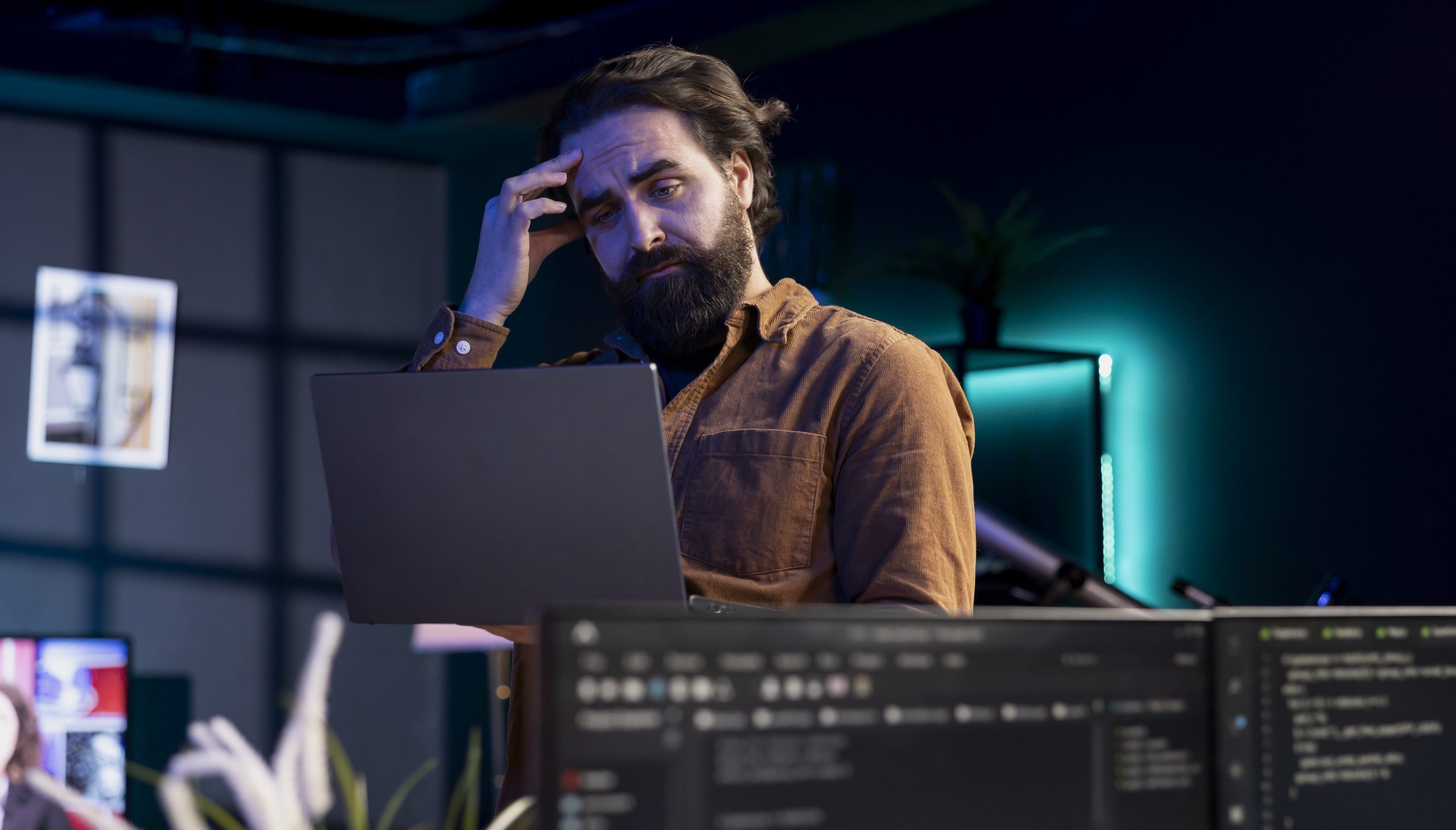 Mensch mit Laptop schaut nachdenklich und hat die Hand am Kopf