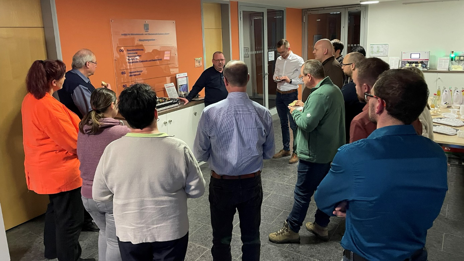 eine Gruppe von Menschen vor einem Wegweiserschild der Verantaltungslocation