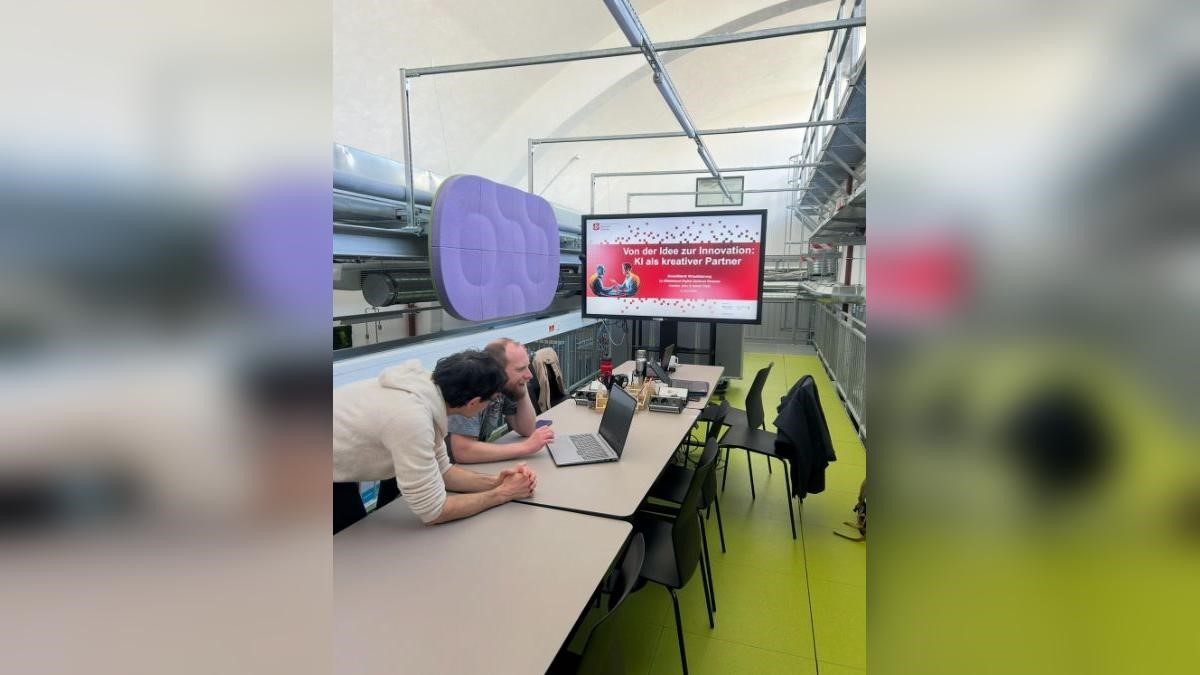 Zwei Menschen sitzen vor einem Laptop im StartUpLab in Jena