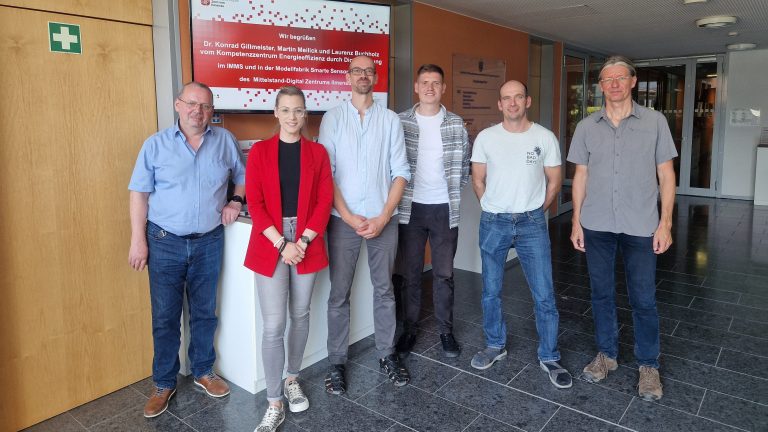 Eine Gruppe Menschen vor einem Bildschirm der sie im Mittelstand-Digital Zentrum Ilmenau willkommen heißt