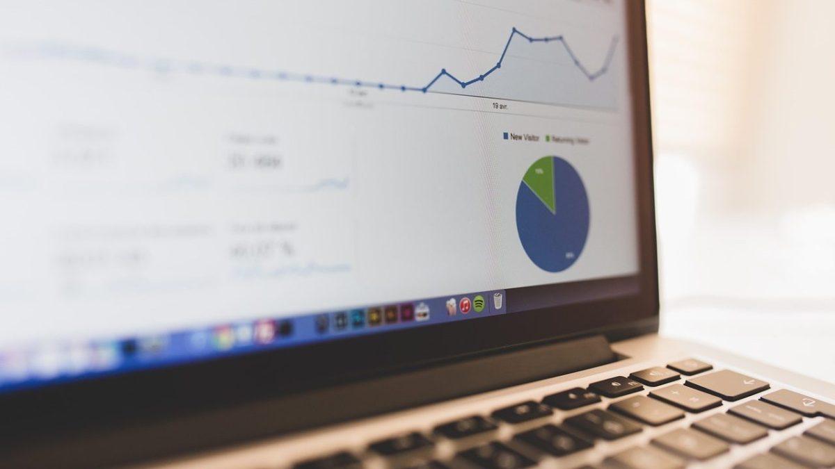 Nahaufnahme eines Laptop-Bildschirms mit Datenanalyse-Dashboard, das ein Liniendiagramm und ein Kreisdiagramm mit den Kategorien ‚New Visitor‘ und ‚Returning Visitor‘ zeigt.